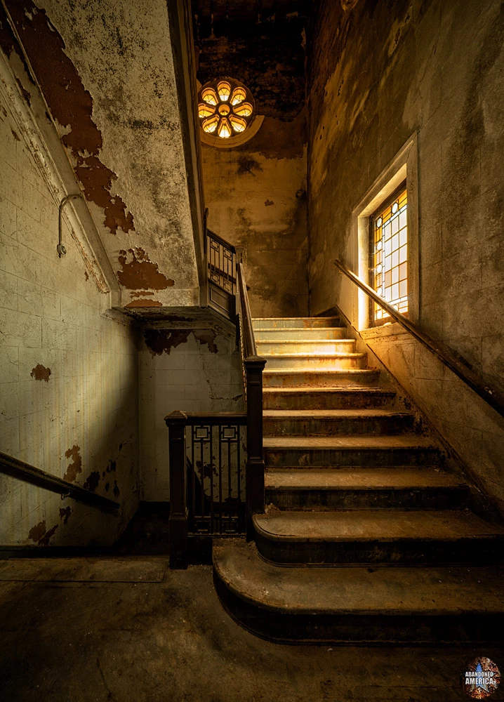 Marble stairs leading to the dome level, paint peeling, light still finding its way through.